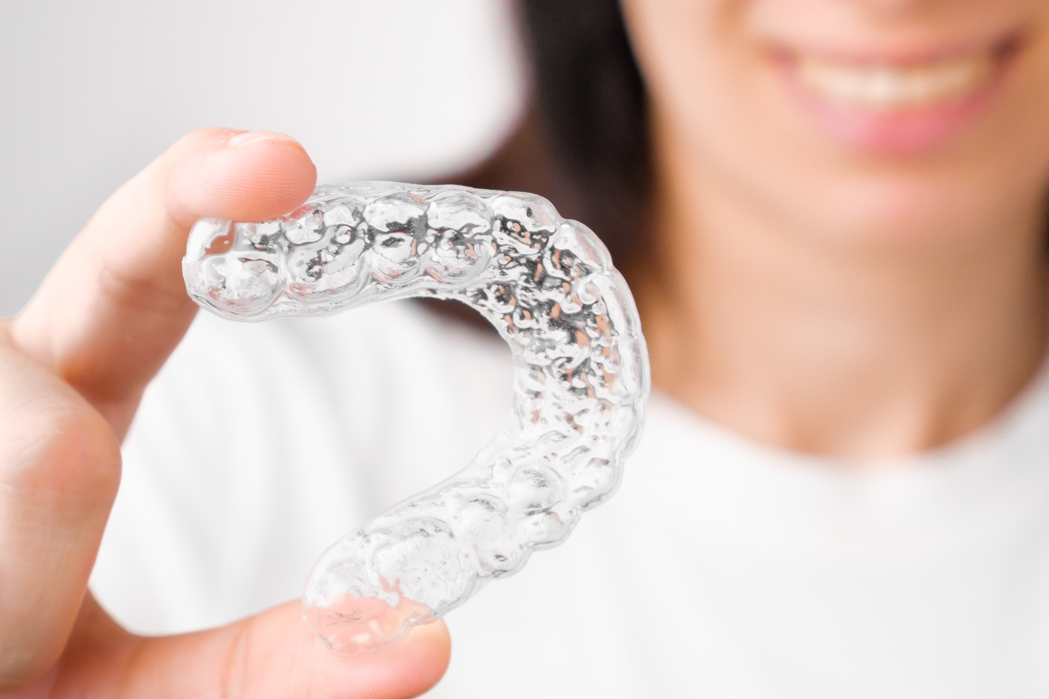 Close up orthodontic transparent aligner in womans hand. Removable braces.